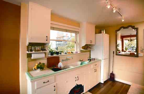 The kitchen has the original painted wooden cabinets and tile countertops. The large gilt mirror adds a sense of space, light and elegance to the room.